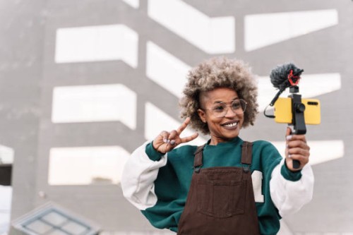 trendy african american woman influencer filming video with smartphone doing peace victory sign with hand - fashion stock pictures, royalty-free photos & images