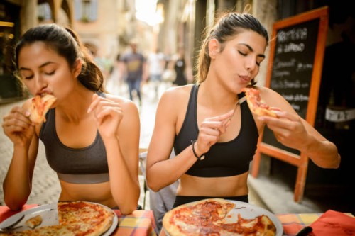 twee sportieve vrouw pizza eten. - junk food stockfoto's en -beelden