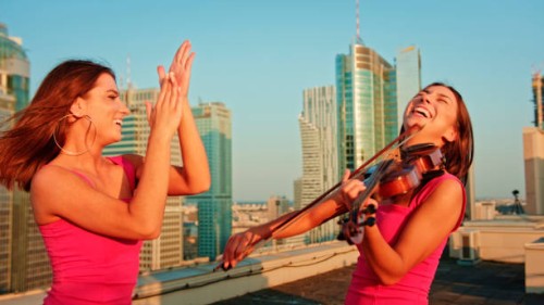 twin sisters enjoying rooftop violin session. playing and dancing - concert stock pictures, royalty-free photos & images