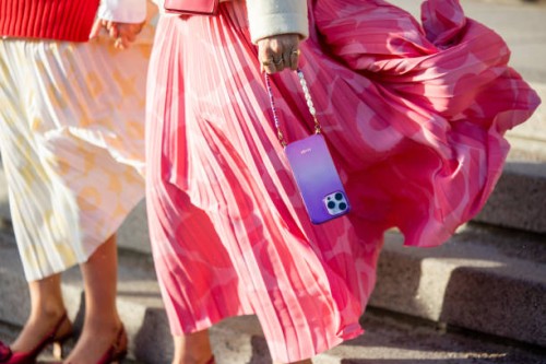 Twins Alice & Olivia Minns wears red vest, beige belted jacket, jumper, pleated skirt, iphone chain outside Marimekko during the Copenhagen Fashion...