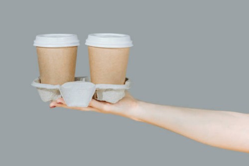 two brown disposable coffee cups on a cardboard rack isolated on a gray background. hygienic cooking or home delivery concept. banner, template, copy space - junk food stock pictures, royalty-free photos & images