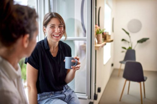 two businesswomen having a coffee break at the window in office - coffee stock pictures, royalty-free photos & images