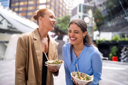 two businesswomen smiling and enjoying healthy bowls outdoors in sydney downtown - junk food stock pictures, royalty-free photos & images
