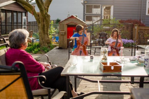 two children give cello concert for grandmother at dinner table - concert stock pictures, royalty-free photos & images