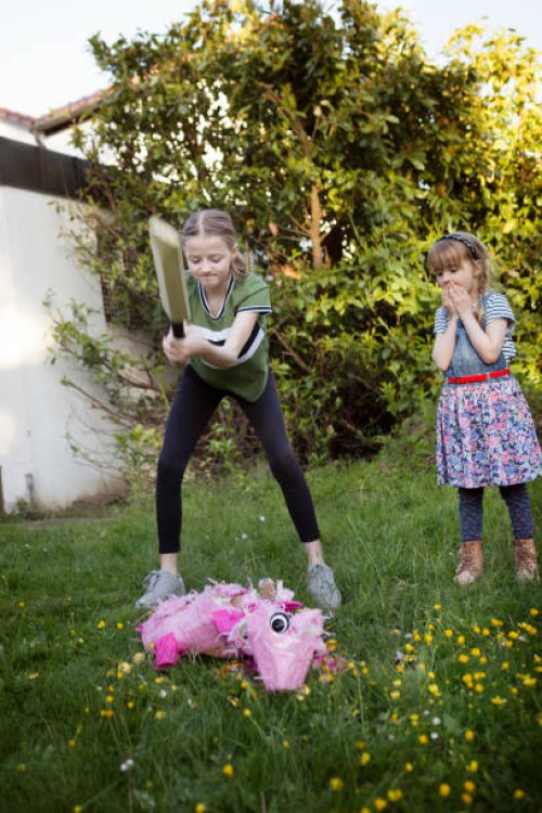 two children hitting a pink pig pinata with a sports bat in a back yard - garden decoration stock pictures, royalty-free photos & images