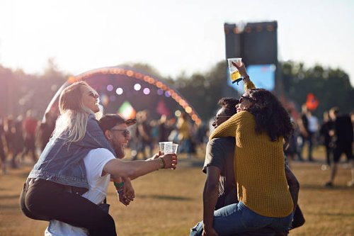 two couples piggybacking at big festival outside - concert stock pictures, royalty-free photos & images