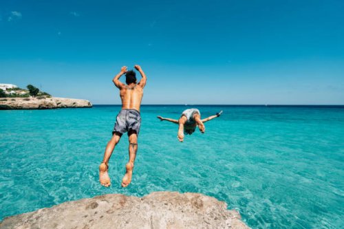 two friends are diving in the sea from a cliff - travel stock pictures, royalty-free photos & images