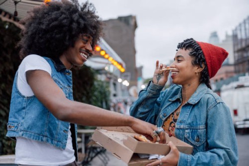 two friends eating pizza on the street - junk food stock pictures, royalty-free photos & images