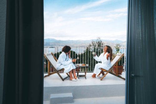 two friends having a good time drinking tea with the scenic view on the balcony - travel stock pictures, royalty-free photos & images