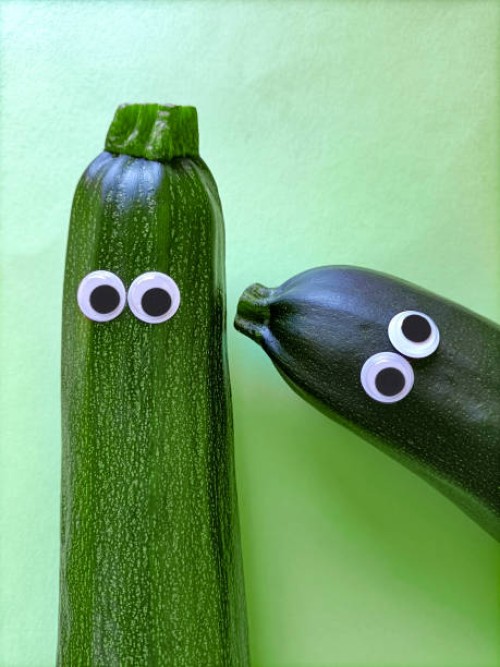 two funny zucchini with cartoon eyes on green background - food stockfoto's en -beelden