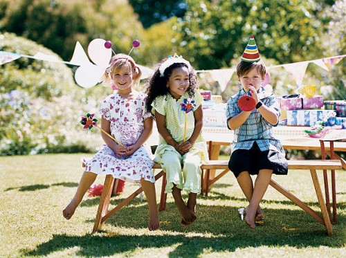 two girls and one boy sitting at a garden table at a birthday party - garden decoration stockfoto's en -beelden