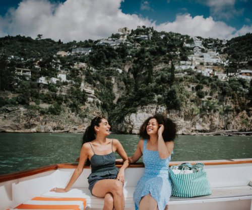 two happy female friends enjoy a boat transfer as they vacation in italy - travel stock pictures, royalty-free photos & images