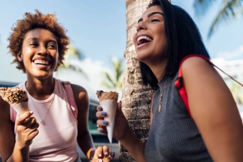 two happy female friends with ice cream cones at a palm tree - food stockfoto's en -beelden