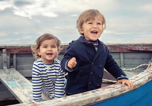 two smiling children playing in a worn rowboat - fashion stock pictures, royalty-free photos & images