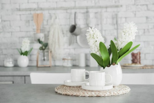 two white cups and vase of flowers on table. decor accessories in kitchen in light colors. - home decoration stockfoto's en -beelden