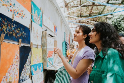 two woman admire paintings at a market stall as they vacation in europe - travel stock pictures, royalty-free photos & images