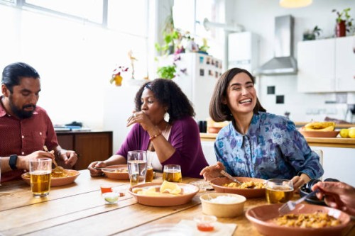 two women and man sitting at table eating takeaway curry together - junk food stock pictures, royalty-free photos & images