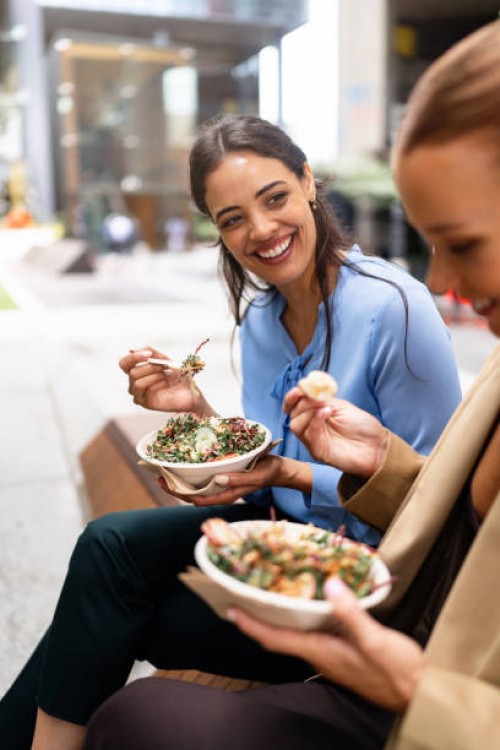 two women enjoying healthy salads outdoors in downtown sydney - junk food stock pictures, royalty-free photos & images