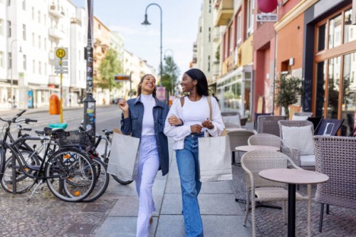 two women friends smiling with shopping bags walking in the city - fashion stock pictures, royalty-free photos & images