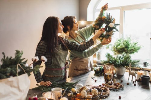 two women making christmas wreath using fresh pine branches and festive decorations. - home decoration stock pictures, royalty-free photos & images