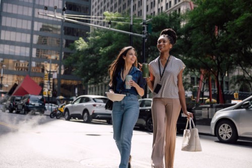 two women office workers crossing the street in manhattan with take away food for lunch break - junk food stock pictures, royalty-free photos & images