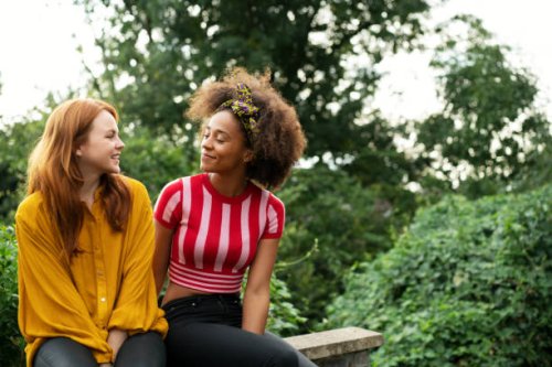 two women sat on wall - hairstyle stock pictures, royalty-free photos & images