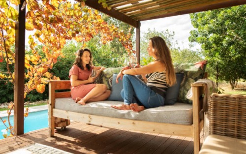 two women sitting on a patio and talking over glasses of wine - home decoration stock pictures, royalty-free photos & images