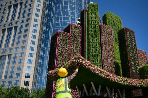 Two workers set up parterre decorations by a corner of a street in Beijing on June 17, 2021.