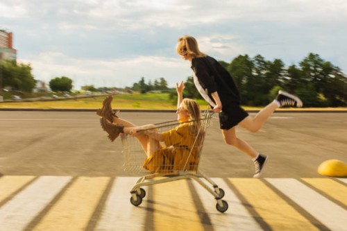 two young blonde girls have fun with shopping cart. fashion woman - fashion stock pictures, royalty-free photos & images
