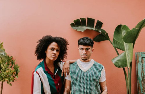 two young, fashionable models look confident as they stand beside each other and look at the camera - fashion stock pictures, royalty-free photos & images