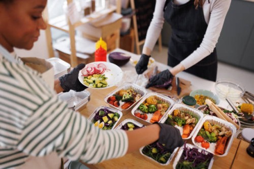 two young female chefs packing food for delivery in aluminum plates at their small domestic food store - food stock pictures, royalty-free photos & images