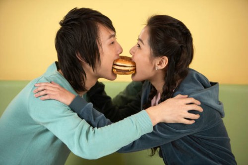 two young friends eating a hamburger. - junk food stock pictures, royalty-free photos & images