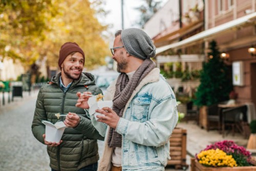 two young man eating fast food outdoors - junk food stock pictures, royalty-free photos & images
