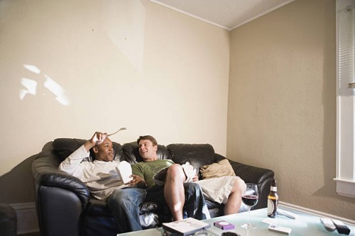 two young men, a gay couple, relaxing on a sofa - junk food stock pictures, royalty-free photos & images