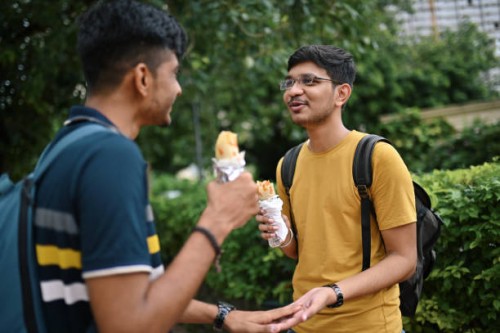 two young men standing on a city street and eating taco - junk food stock pictures, royalty-free photos & images