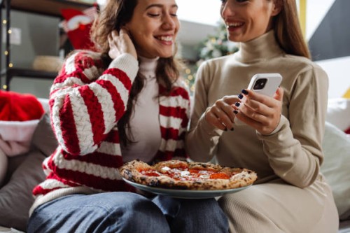 two young woman ordering pizza for a cozy night in - junk food stock pictures, royalty-free photos & images