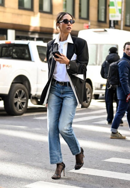 TyLynn Nguyen is seen wearing a black blazer, white shirt, blue jeans, black heels and black sunglasses outside the Calvin Klein show during NYFW F/W...