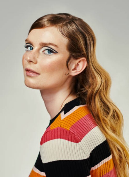 une jolie jeune femme habillée en tenue des années 60 sur un fond de studio gris. portrait d’un beau mannequin regardant l’appareil photo habillé dans un style rétro - hairstyle photos et images de collection