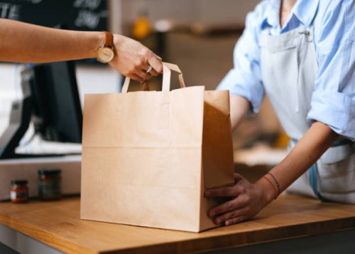unrecognizable female employee giving packed order to a customer - junk food stock pictures, royalty-free photos & images