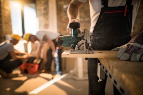unrecognizable worker cutting plank with circular saw at construction site. - home decoration stock pictures, royalty-free photos & images