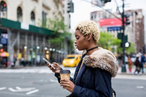 usa, new york city, fashionable young woman with coffee to go looking at cell phone on the street - hairstyle stock pictures, royalty-free photos & images