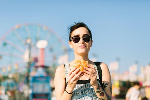 usa, new york, coney island, young woman eating a hamburger - junk food stock pictures, royalty-free photos & images