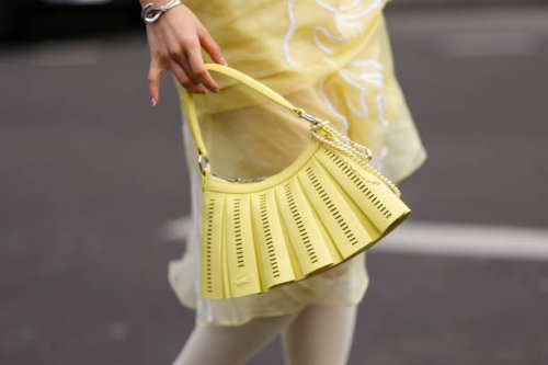 Valerie Zhang wears a shiny bright yellow Lacoste leather bag, outside Lacoste, during the Paris Fashion week Women's Fall/Winter 2025-2026 on March...
