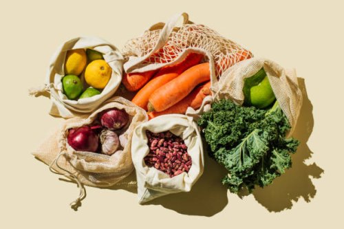 variety fresh of organic fruits and vegetables and healthy vegan meal ingredients in reusable eco cotton bags on beige background . zero waste shopping concept. healthy food, clean eating, eco friendly, no plastic. flat lay, 