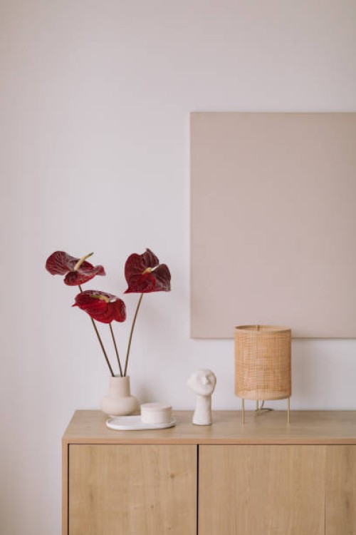 vase with anthurium flowers and ornaments on a wooden sideboard with blank artwork on the wall - fashion stock pictures, royalty-free photos & images