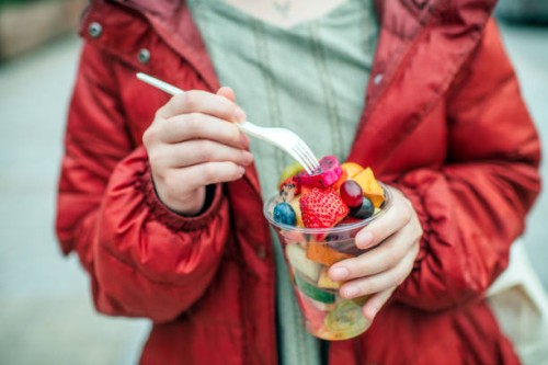 vegan woman eating fruit salad outdoors - junk food stock pictures, royalty-free photos & images