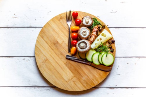 vegetables on round chopping board, symbol for intermittent fasting - food stock pictures, royalty-free photos & images