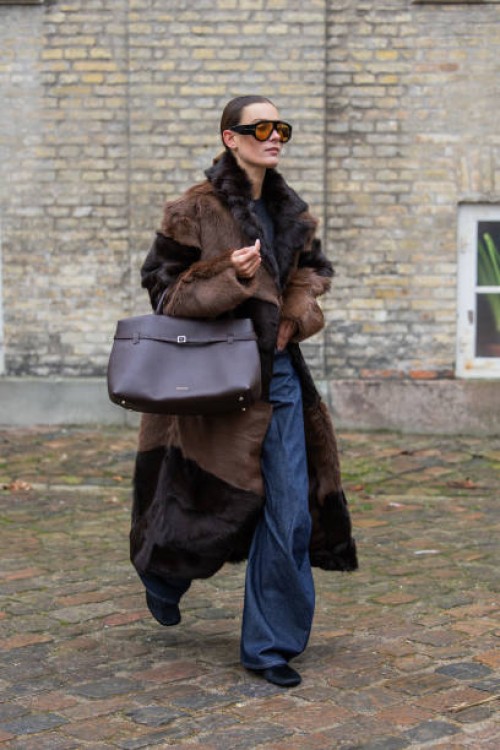 Vera van Erp wears brown black two tone fur coat, Manu Atelier bag, denim jeans, sunglasses outside TG Botanical during the Copenhagen Fashion Week...