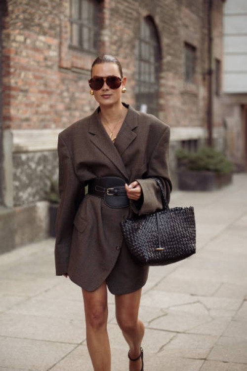 Vera van Erp wears oversized brown blazer with black wide leather belt, sunglasses, back bag outside the Rotate show during day four of the...