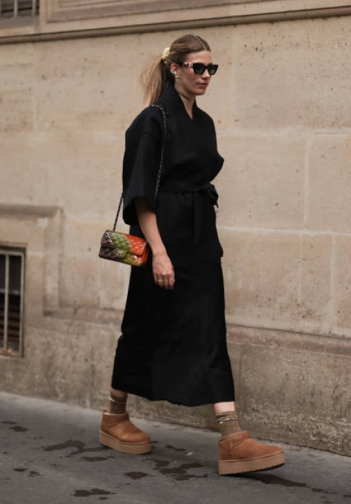 Veronika Heilbrunner seen wearing black sunglasses, black kimono shaped jacket, black silk long skirt, gold choker necklace and earrings, colorful...
